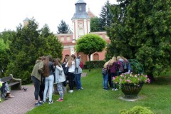 Kilka osób rozwiązuję zadanie, w tle widać kościół.