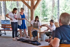 sześć osób uczy się plecionkarstwa, w tle drzewa