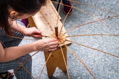 osoba robi podstawę koszyka z wikliny na ławce