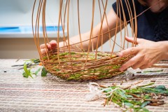 osoba robiąca kosz z wikliny z listkami