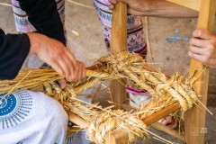 dwie osoby robią siedzisko ze słomy w drewnianym krześle