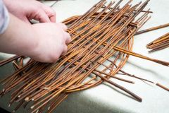 dłonie wyplatające ozdobe z wikliny