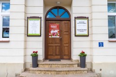 Wejście do Muzeum Kultury Kurpiowskiej. Na drzwiach biało-czerwony plakat reklamujący imprezę patriotyczną.