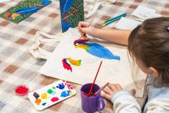 Dziewczynka malująca kolorowe ptaki na płóciennej torbie