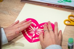 Dłonie przytwierdzające wycinankę w kształcie serca do kartki papieru