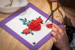 Dłonie operujące nożyczkami podczas tworzenia dekoracji w ramce