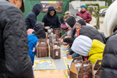 Uczestnicy pikniku Fortach Bema stojąc przy stole przy rozwiązują zadania na mapach. Na stole znajdują się tekturowe  walizki i materiały edukacyjne