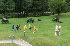 Uczestnicy pikniku na Fortach Bema podczas biegu z tekturowymi końmi na kiju. W tle Skansen Artylerii oraz ulica Warszawska