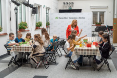 dzieci siedzą stole i wycinają karteczki 