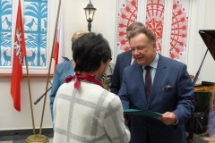 Mężczyzna zostaje wręczony przez kobietę stojące przy yortepienia i mikrofonie