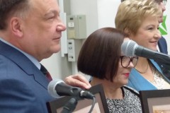 Cztery osoby pozujące dla zdjęcia trzymając dyplomy stojące przy mikrofonie