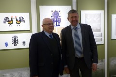 2 mężczyzn pozuje do zdjęcia na tle obrazów 