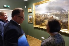 Na zdjęciu osoby rozmawiają razem, w tle znajduje się obraz "Bitwa pod Ostrołęką" Karol Malankiewicz