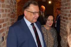 W zabytkowych piwnicach wśród ścian czerwonej cegły stoją kilka osób.