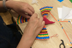 Damskie dłonie doczepiają ogon własnoręcznie robionemu ptaku.