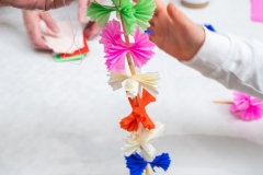 Mężczyzna podaje do ręki dziecku łańcuch z bibuły.