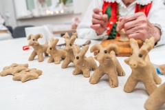 Na blacie stoi kilka byśków, w tle dłonie osoby w stroju kurpiowskim.