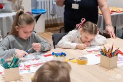 Dwie dziewczynki siedząc przy stole wykonują prace plastyczne