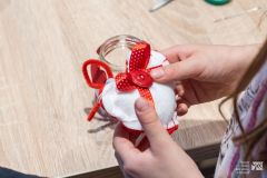 Dłonie trzymające filcowe serce z biało-czerwoną dekoracją