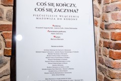 Plakat wystawy na sztaludze w zabytkowej piwnicy