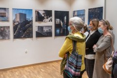 Kilka kobiet w maseczkach przygląda się fotografiom wiszącym na ścianie sali wystawowej.