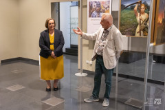Uczestnicy wernisażu stoją w sali wystawowej, w tle dzieła malarskie