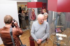 Goście zwiedzają wystawę zabytkowej biżuterii eksponowanej w szklanych gablotach