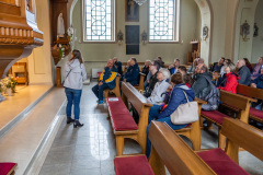 Uczestnicy spaceru wewnątrz kościoła, widok na ławki i prawą nawę boczną