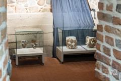 Gabloty, w których znajdują się ceramiczne naczynia. Wokół ściany z cegieł oraz kamienia.