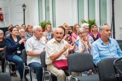 Uczestnicy spotkania siedzą na widowni, niektórzy klaszczą