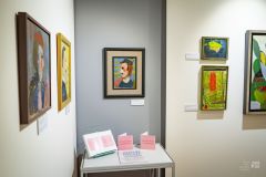 Fragment wystawy dzieł malarskich, stolik z materiałami promocyjnymi wystawy