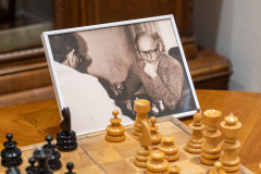 fragment szachownicy, obok fotografia w ramce