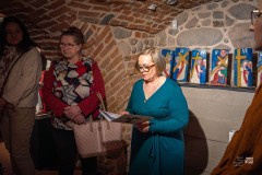 Cztery osoby stoją w zabytkowych piwnicach. W tle ekspozycja płaskorzeźb