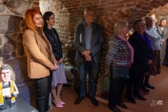 Kilka osób stoi w zabytkowych piwnicach.