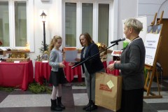 Dziewczynka odbiera nagrodę od kobiet.