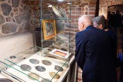 Kobieta i mężczyzna oglądają zabytki w szklanej gablocie na ekspozycji w zabytkowych piwnicach.