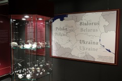 Szklana gablota z biżuterią i ozdobami, w tle widać mapę Polski, Białorusi oraz Ukrainy.
