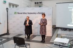 Dwie kobiety stoją, przemawiają do mikrofonów. W tle ścianka z logotypami oraz napisem Muzeum Kultury Kurpiowskiej w Ostrołęce.