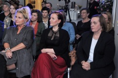 Trzy kobiety siedzą przysłuchując się.