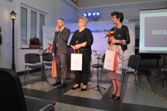Trzy nagrodzone osoby stoją, mężczyzna dziękuje za nagrodę.