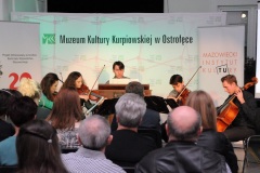 Grupa artystów gra koncert, widownia słucha.
