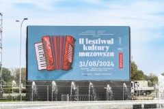 Wielki ekran z bannerem reklamującym 2. Festiwal kultury Mazowsza. Przed ekranem fontanny